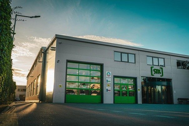 Veľká biela budova so zelenými oknami a nápisom STK, patriaca k autoservisu Biga.